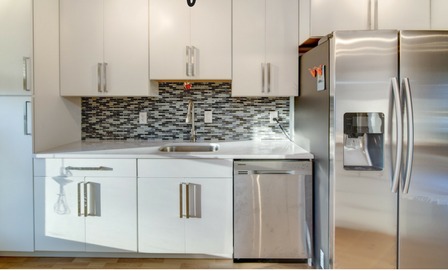 Kitchen after remodel - white shaker cabinets, mosaic backsplash and stainless steel appliances