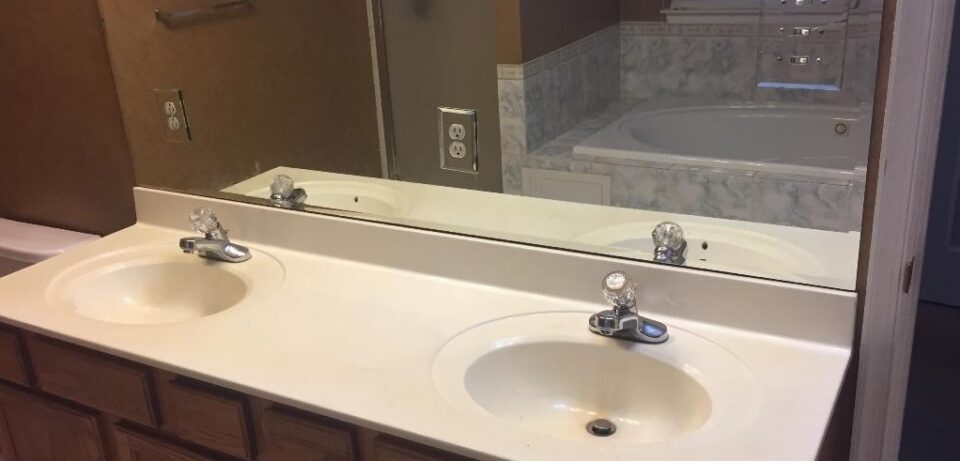 Bathroom vanity before remodel - cultured marble top and builder-grade faucets
