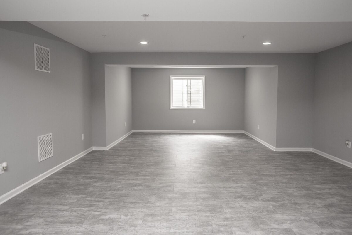Finished basement with gray vinyl plank flooring, gray walls and recessed lighting