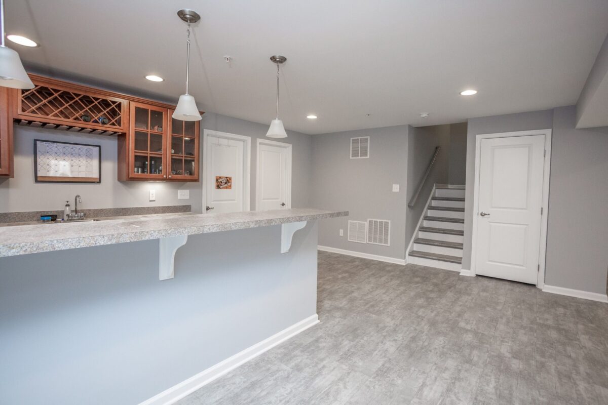 Finished basement wet bar with raised counter, wine rack and pendant lights
