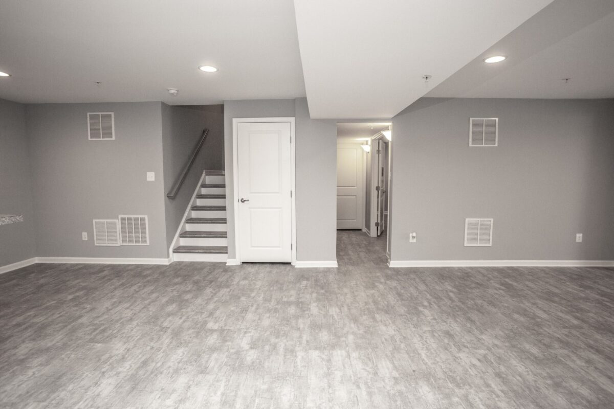 Finished basement with staircase, white doors and gray plank flooring