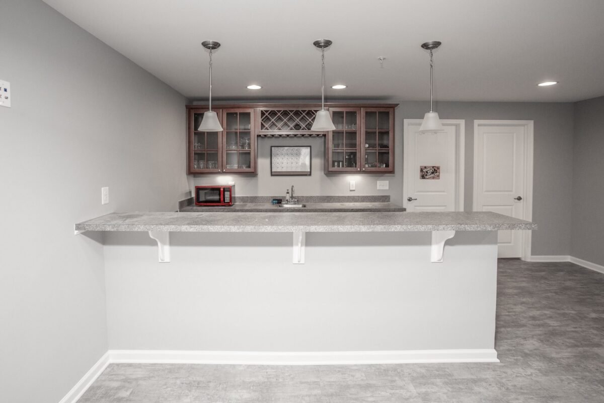 Basement bar with cherry cabinets, wine rack and three pendant lights over the counter
