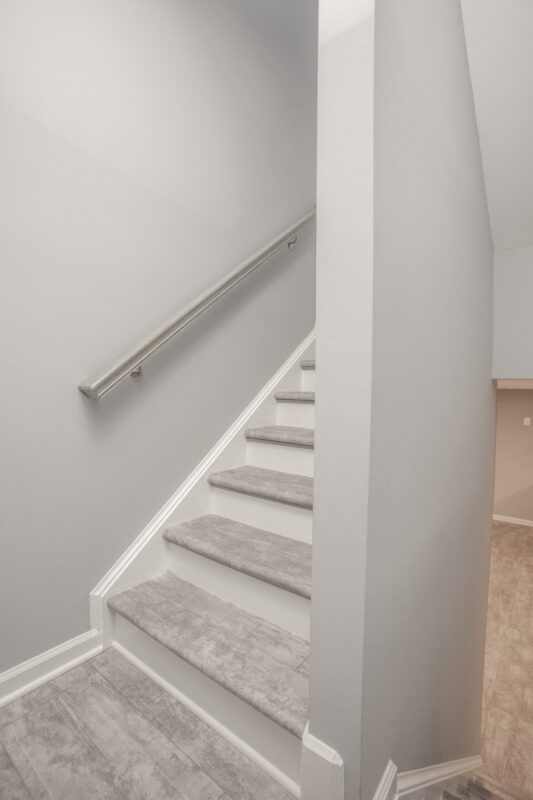 Finished basement stairway with gray treads and brushed nickel handrail