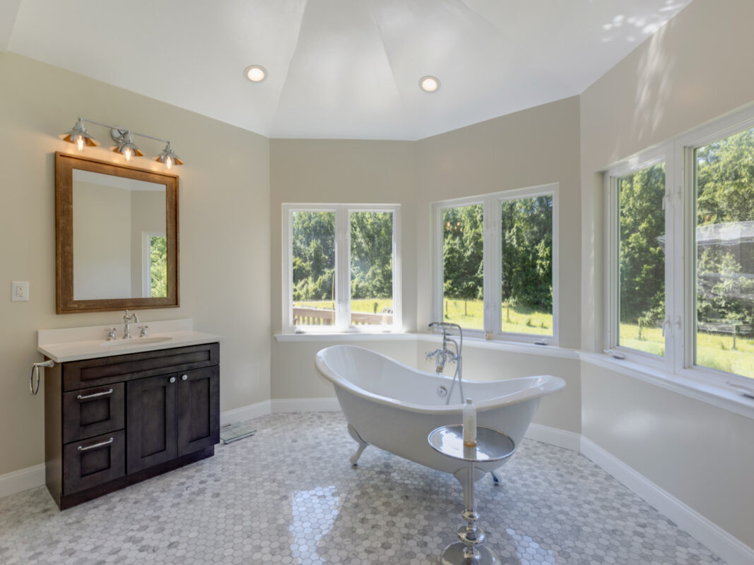 Bathroom with clawfoot soaking tub, pebble tile floor and dark wood vanity