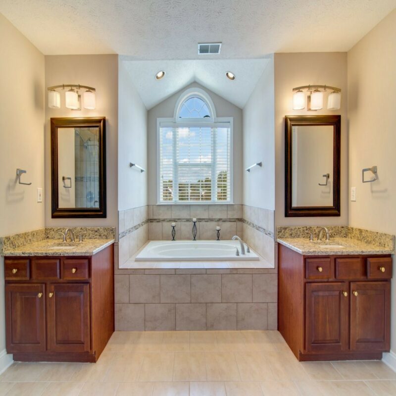 Primary bathroom with twin cherry vanities, granite tops and a soaking tub