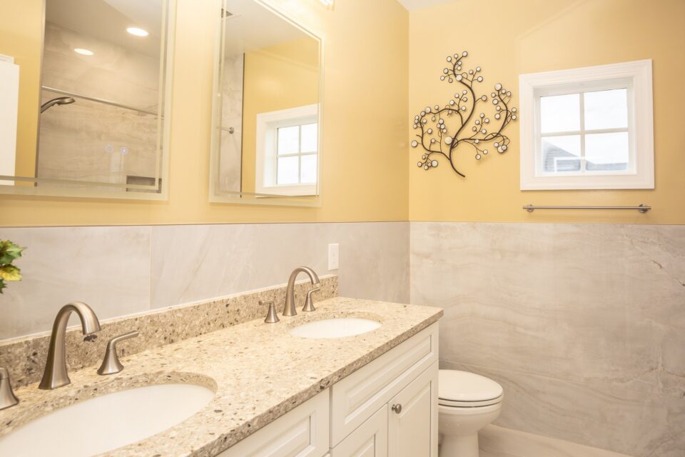 Double vanity with granite countertop, undermount sinks and tile wainscoting