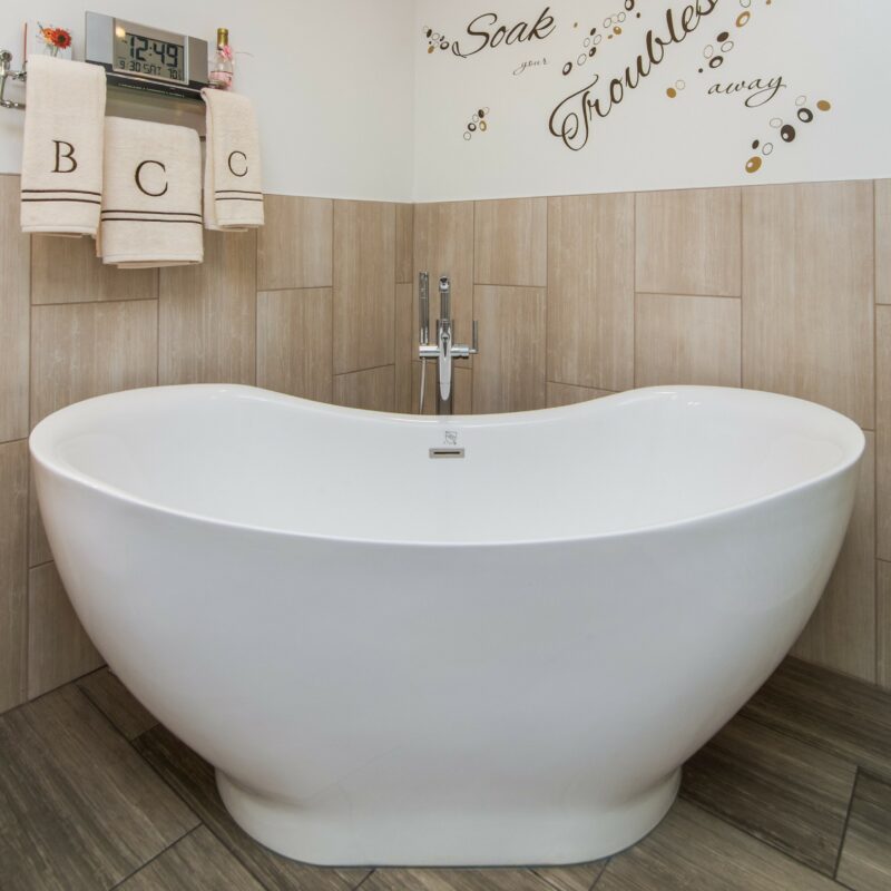 Freestanding soaking tub with floor-mounted faucet and wood-look tile walls