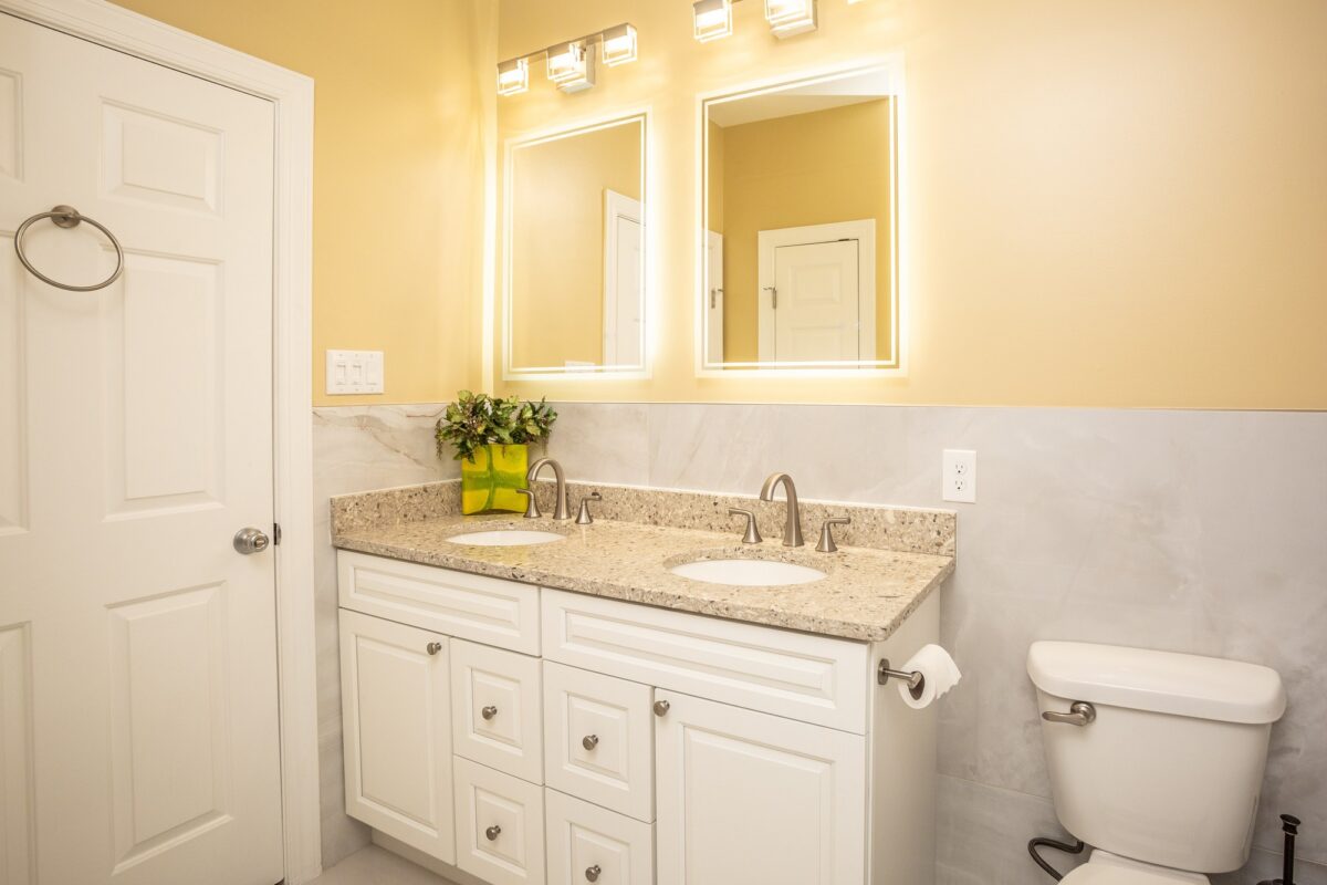 White double vanity with granite top and lighted mirrors
