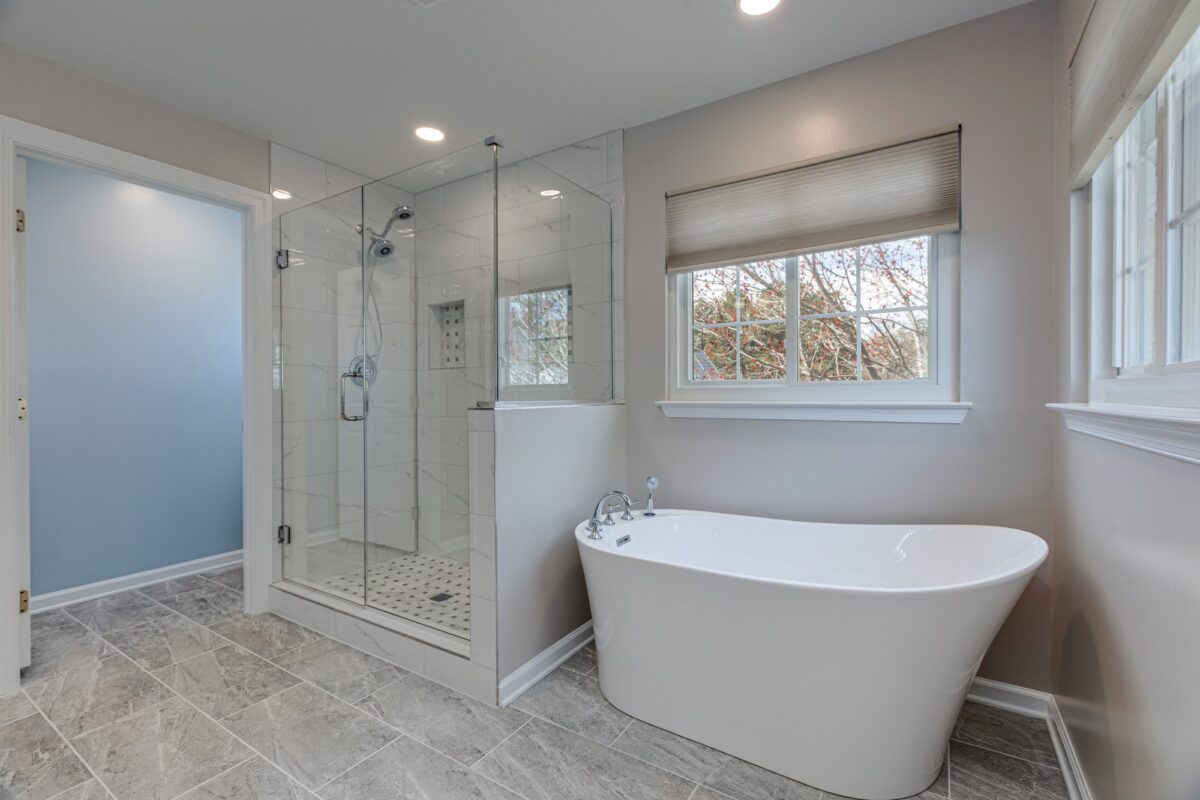 Bathroom with glass walk-in shower and freestanding tub under a window