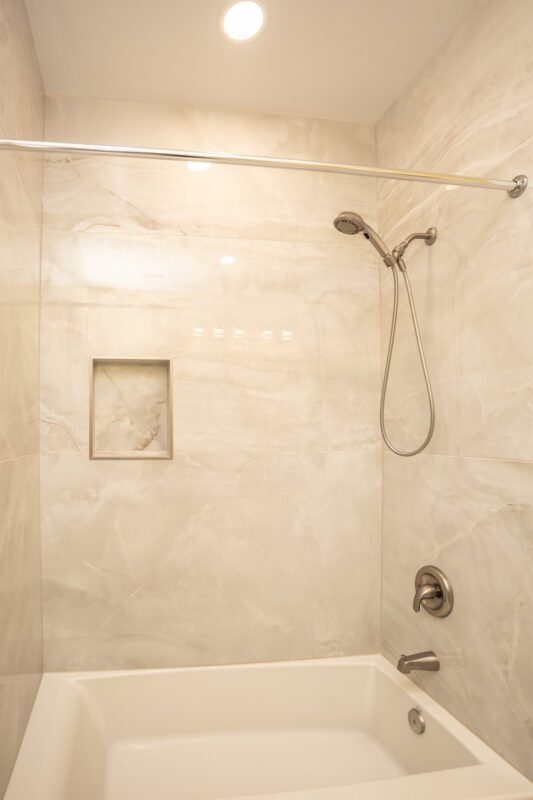 Tub and shower combination with marble-look tile and recessed niche