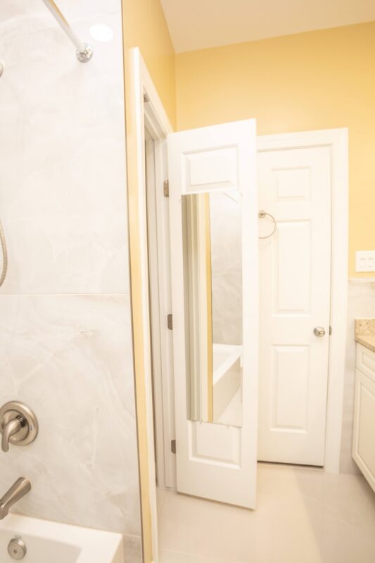 View through a bathroom doorway with marble-look tile shower wall