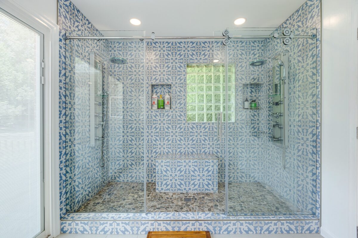Walk-in shower with sliding glass doors, blue patterned tile and glass block window