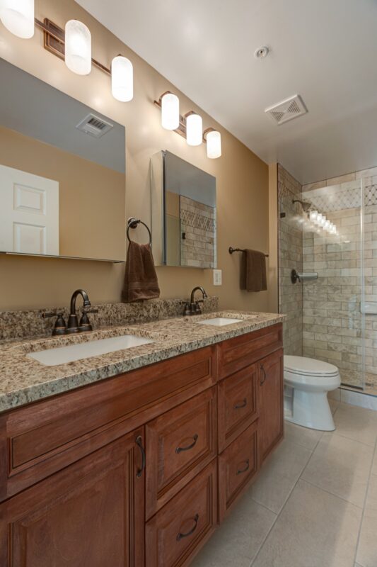 Cherry double vanity with granite top, vanity lights and tiled shower
