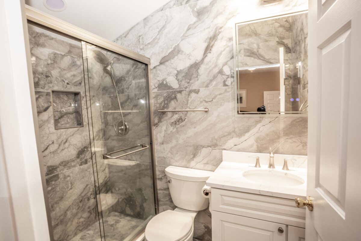 Small bathroom with marble-look tile shower, glass door and white vanity