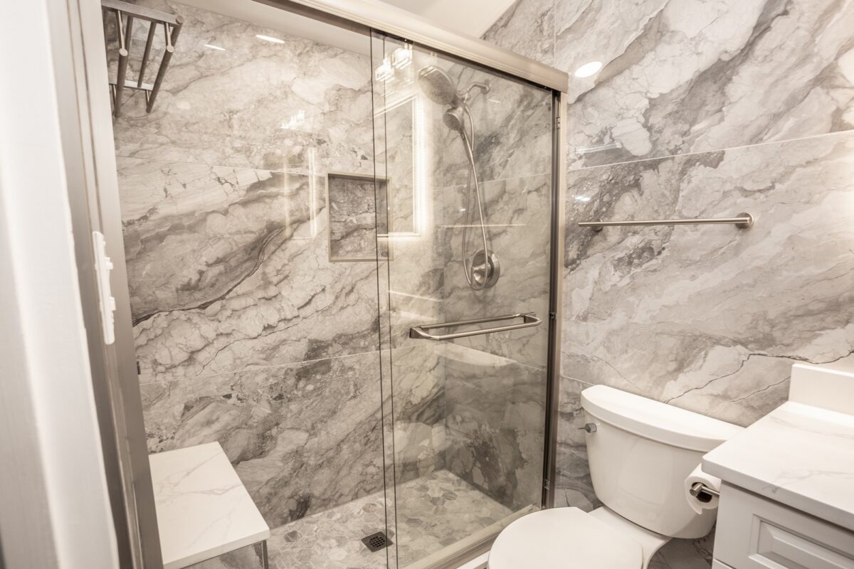 Gray marble-look tile shower with sliding glass door and grab bar