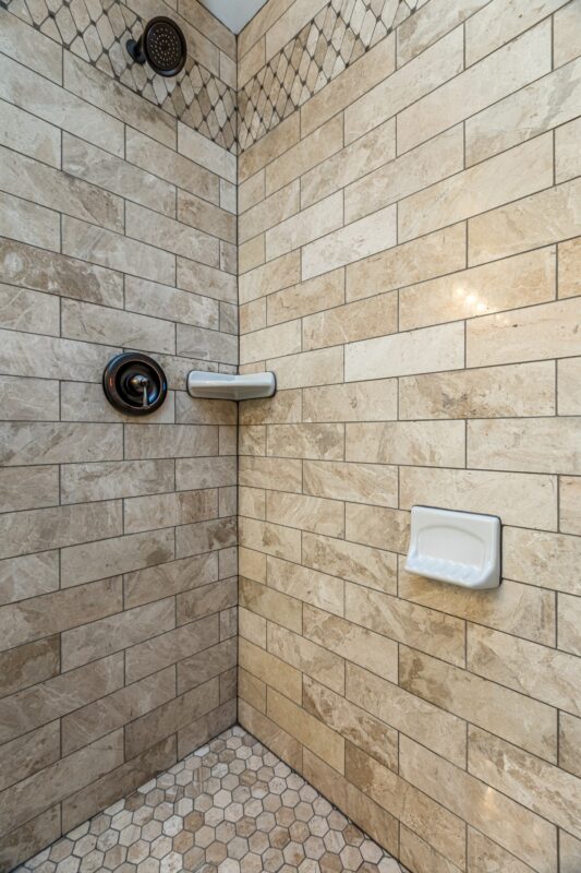 Shower with travertine-look tile, diamond accent band and soap dish