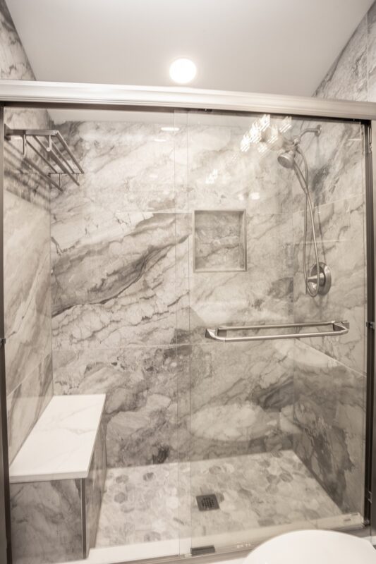 Gray marble-look tile shower with niche, bench and grab bar