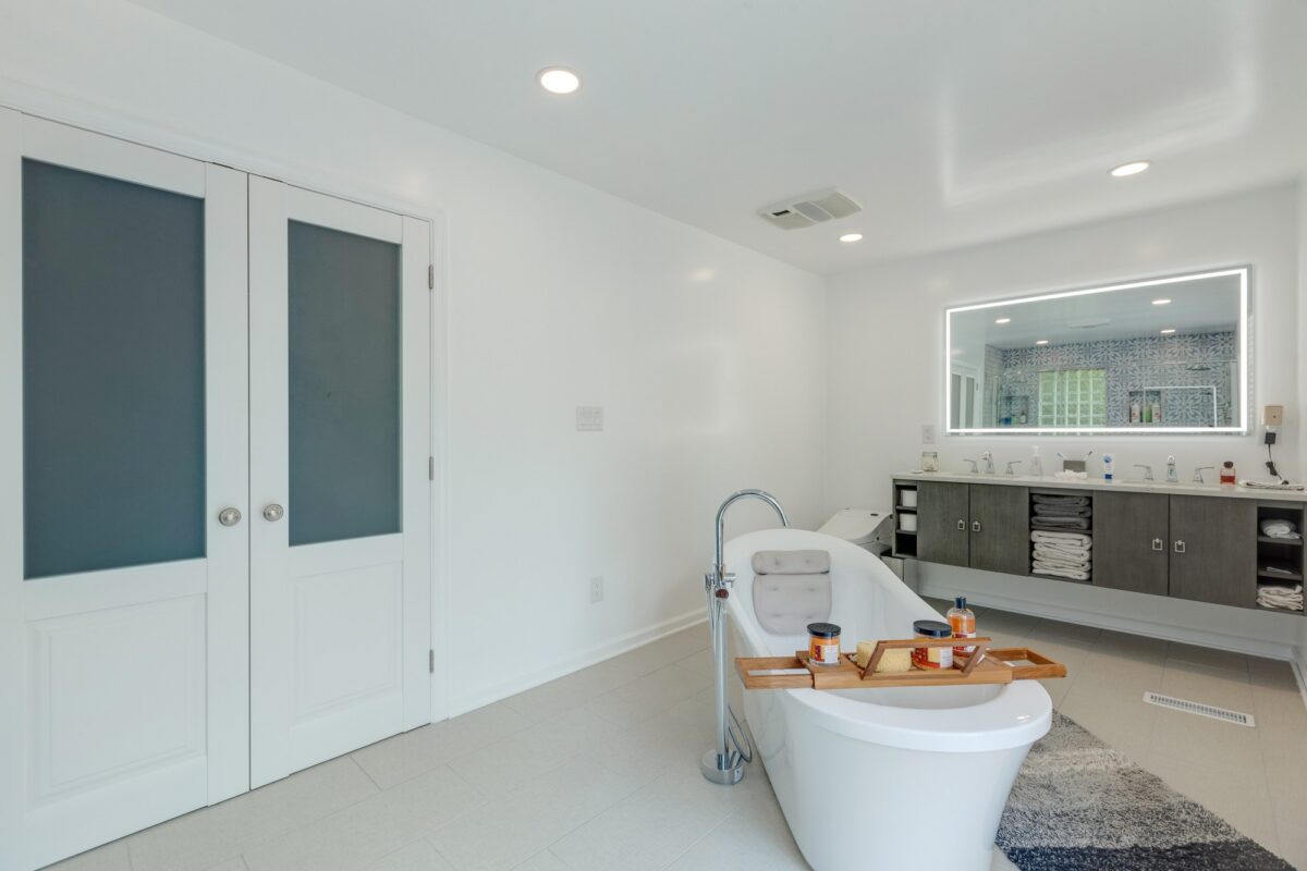 Primary bathroom with frosted glass doors, freestanding tub and floating vanity