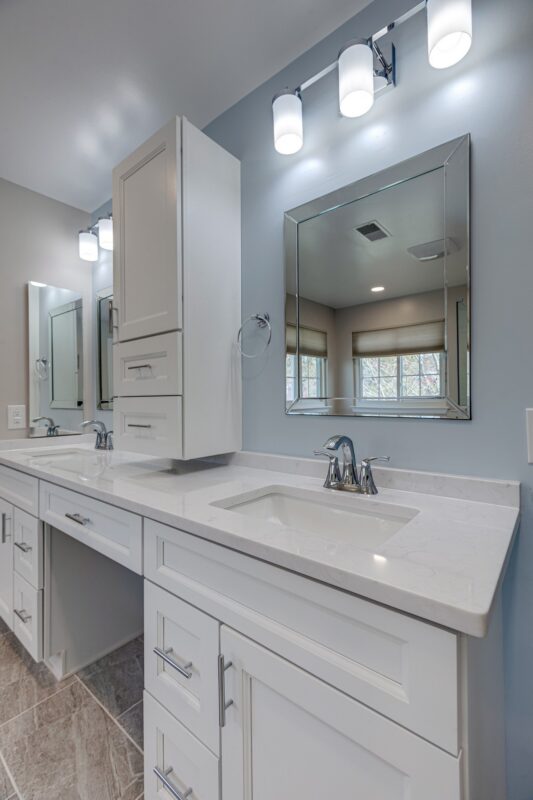 White vanity with makeup counter, tower cabinet and vanity lights