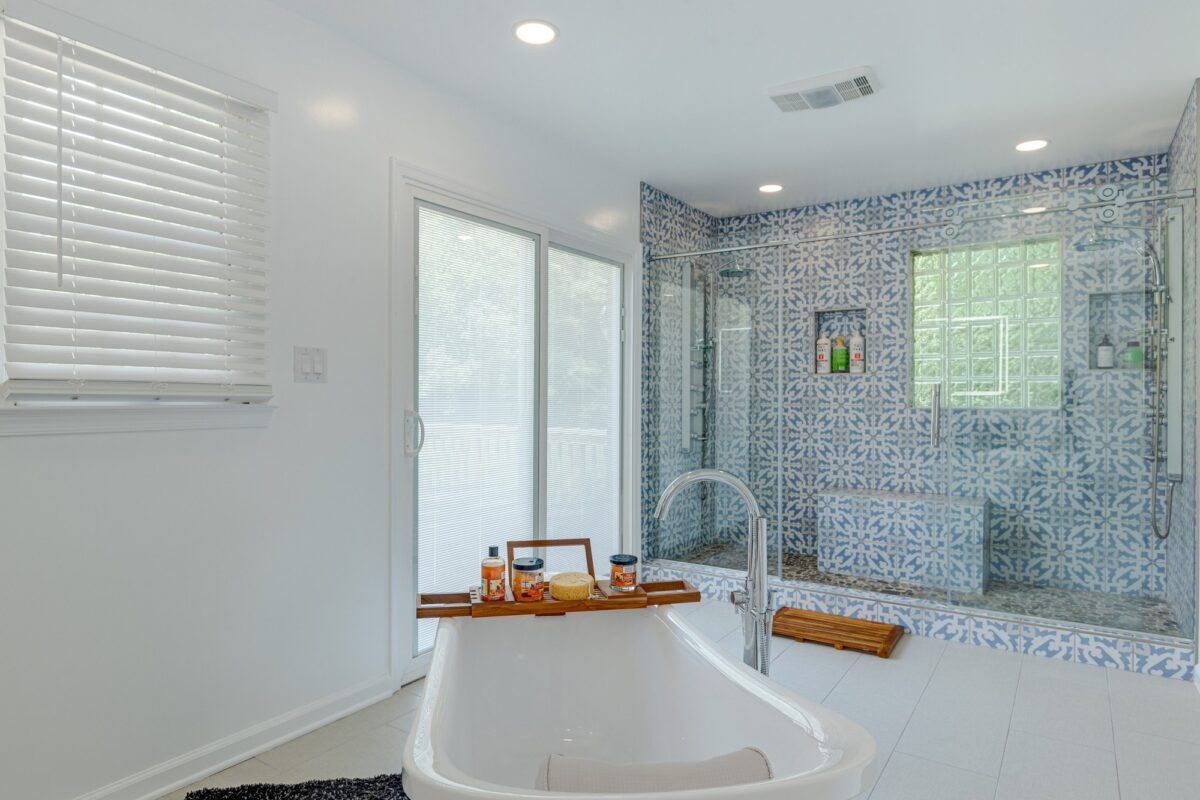 Primary bathroom with freestanding tub and blue patterned tile walk-in shower