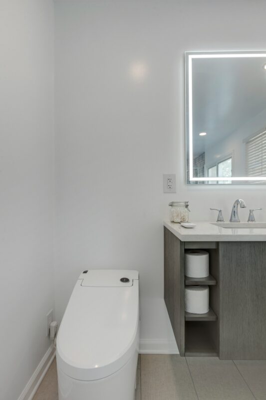 Floating gray vanity with lighted mirror and smart toilet