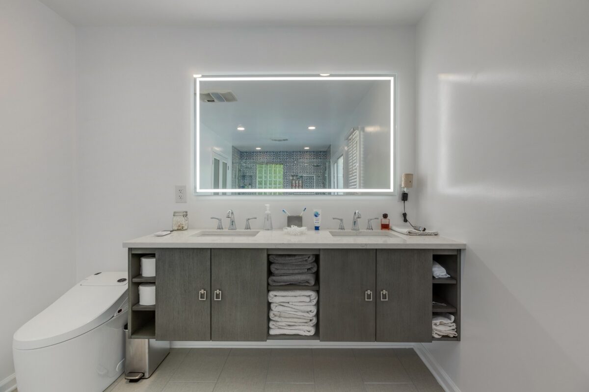 Floating gray double vanity with open towel shelves and lighted mirror