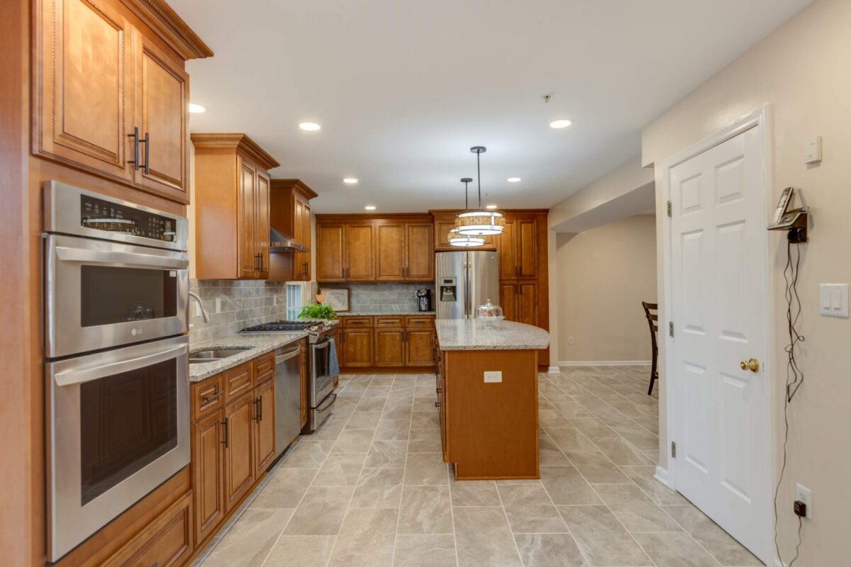 Long kitchen with wood cabinets, stainless appliances and tile floor