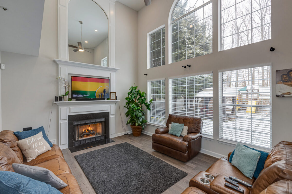 Two-story family room with fireplace, tall windows and leather sofas