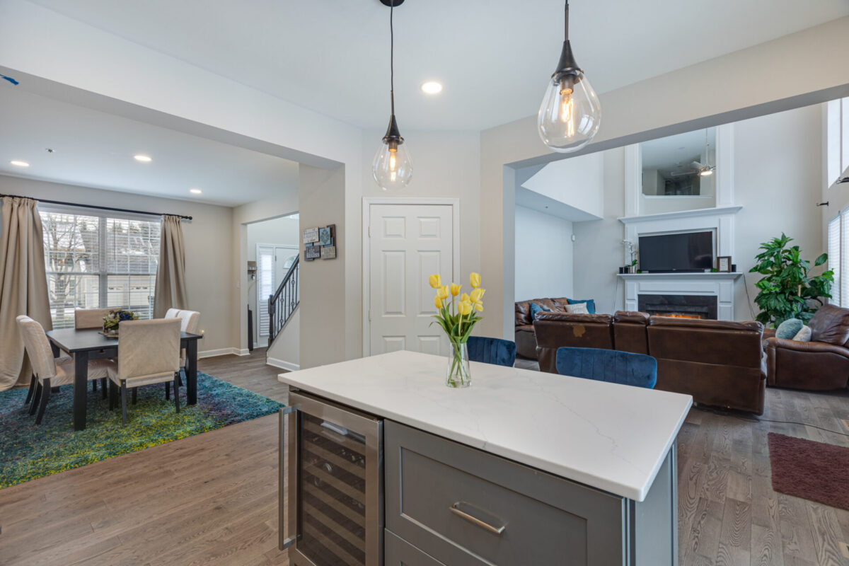 Open kitchen island with wine fridge looking into the dining and family rooms