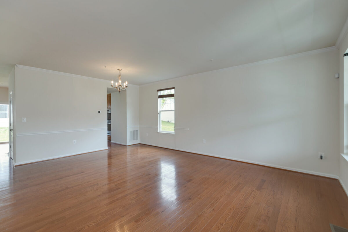 Open living and dining area with hardwood floors and chandelier