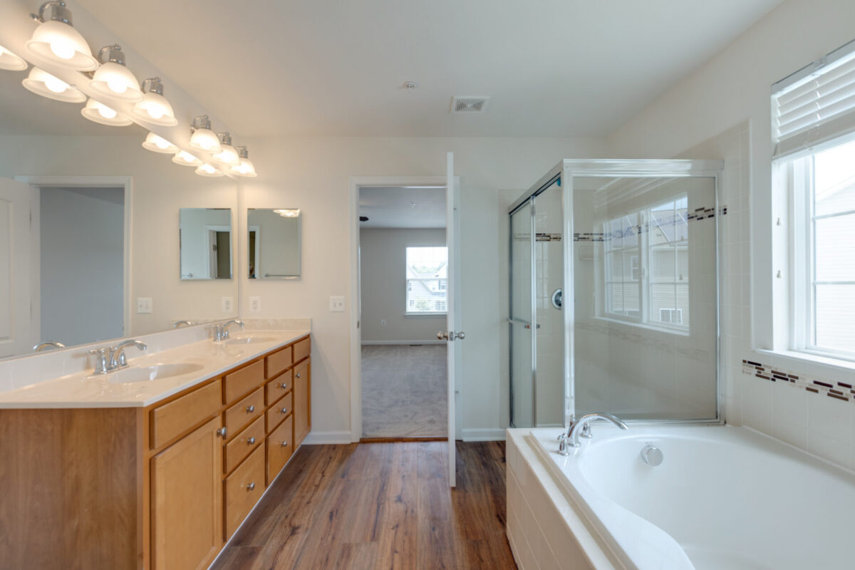 Primary bathroom with wood double vanity, soaking tub and glass shower