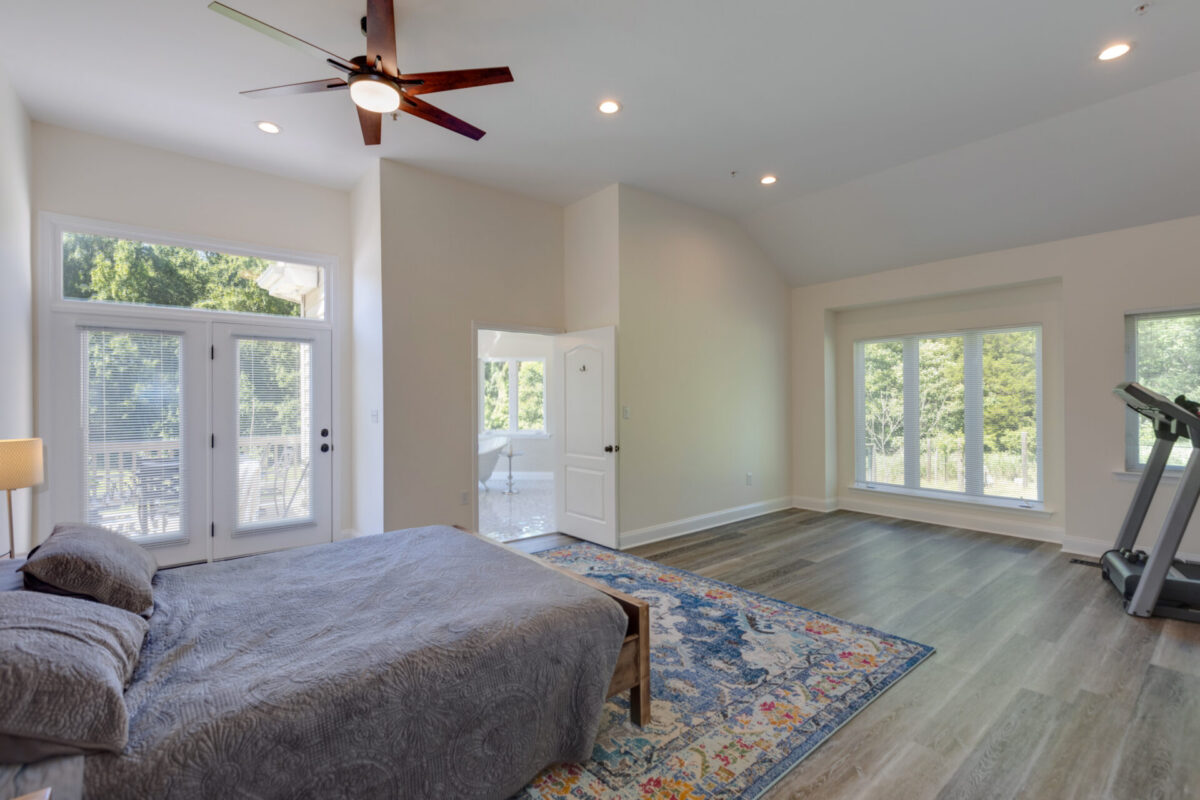 Bedroom with vaulted ceiling, ceiling fan, French doors and plank flooring