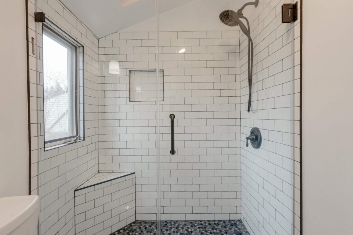 White subway tile shower with niche, bench and black fixtures
