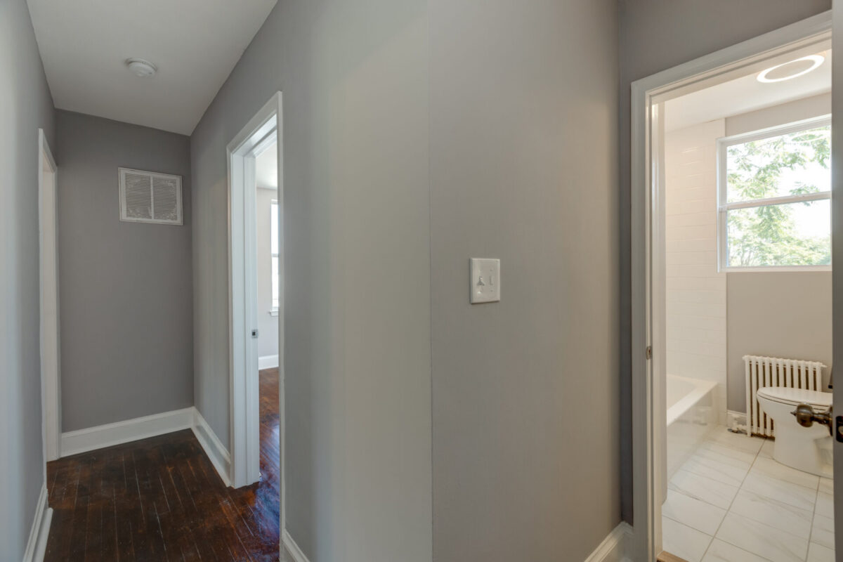 Remodeled hallway with gray walls and dark wood floors