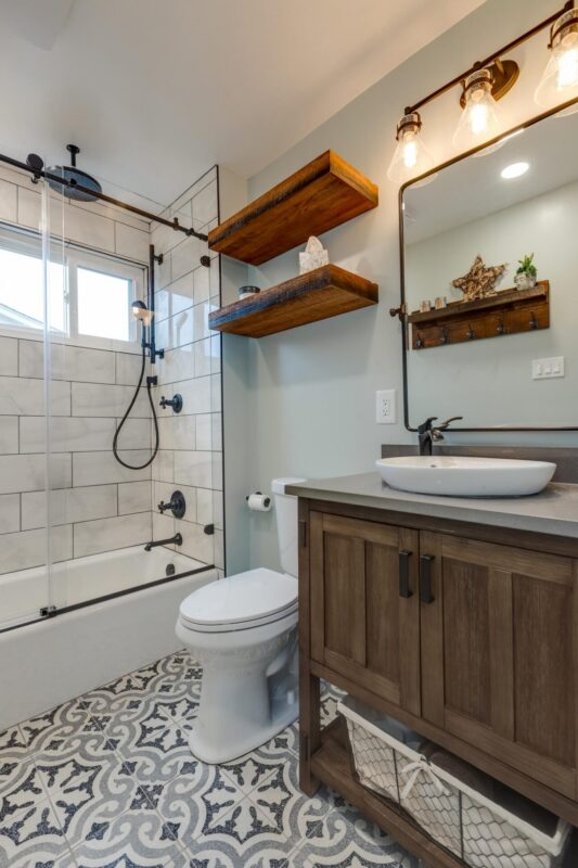 Bathroom with patterned tile floor, wood vanity, vessel sink and floating shelves