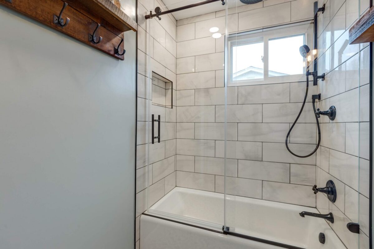 Tub and shower with large gray tile, niche and black fixtures