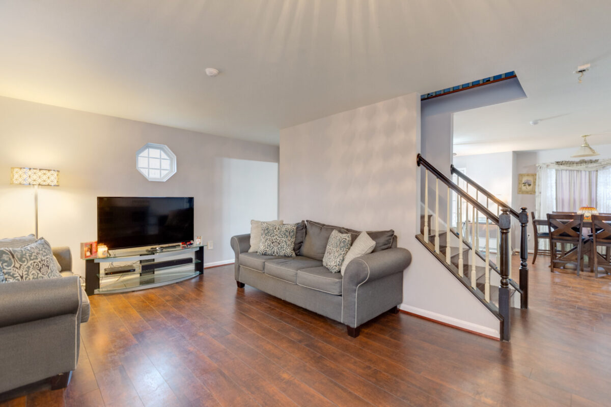 Living room with wood floors, staircase and dining area beyond