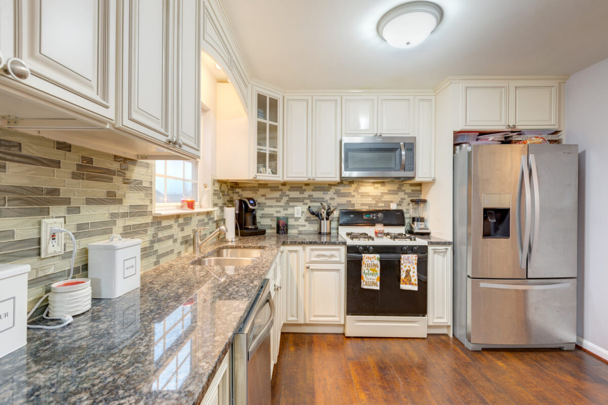 Kitchen with cream cabinets, granite counters and stone backsplash