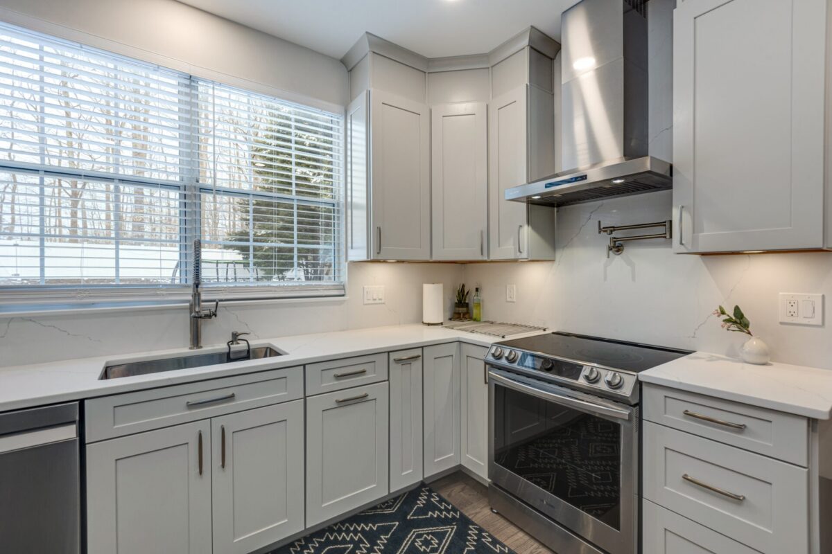 Gray shaker kitchen with stainless range hood and quartz counters