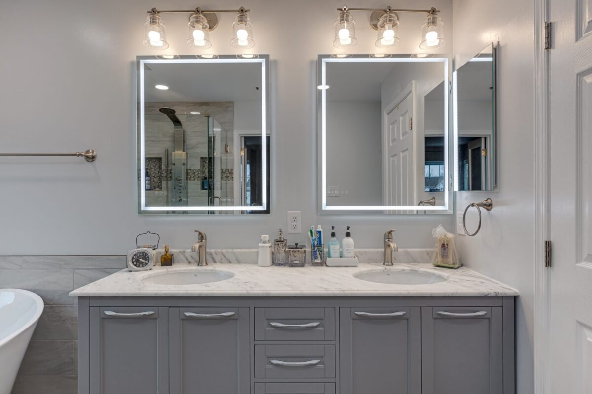 Gray double vanity with marble top and lighted mirrors