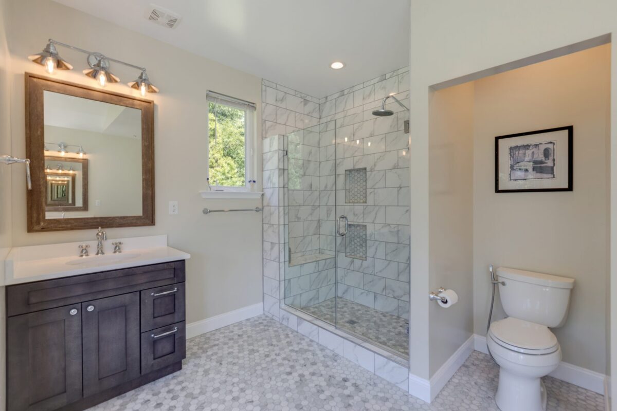 Bathroom with espresso vanity, wood mirror and glass tile shower
