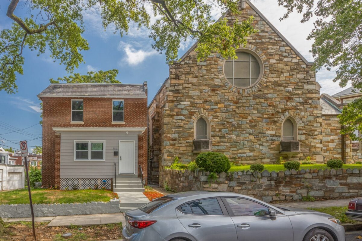 Exterior of a renovated brick row house beside a stone church