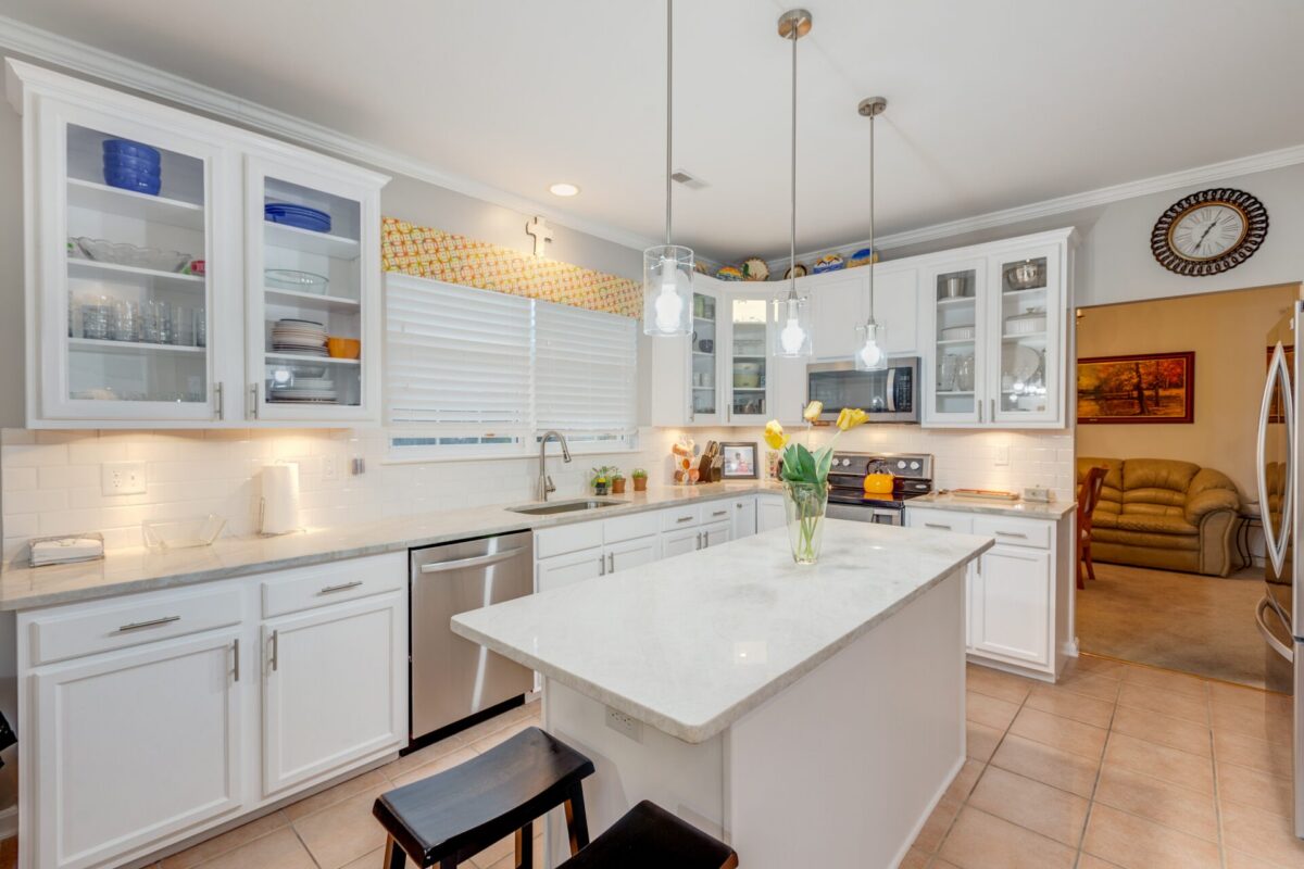 White kitchen with island, glass-front cabinets and pendant lights