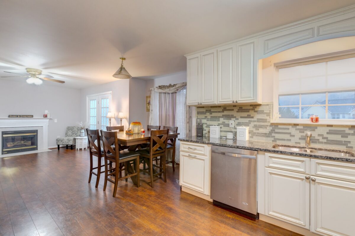 Open kitchen and dining room with white cabinets, fireplace and wood floors