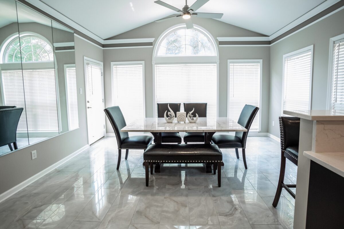 Dining area with vaulted ceiling, arched windows and marble-look tile floor