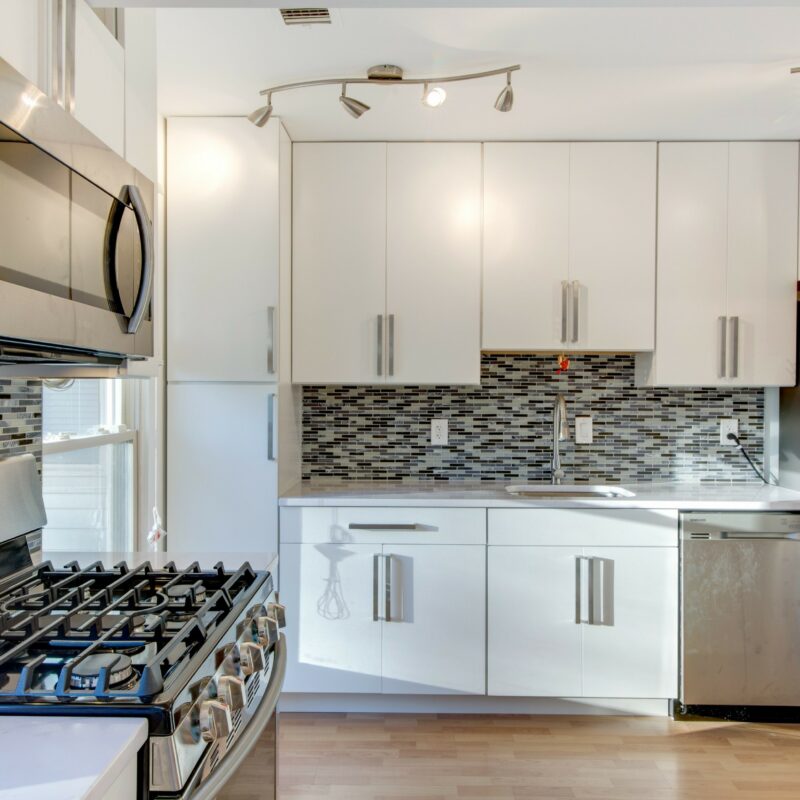 White kitchen with glass mosaic backsplash and gas range