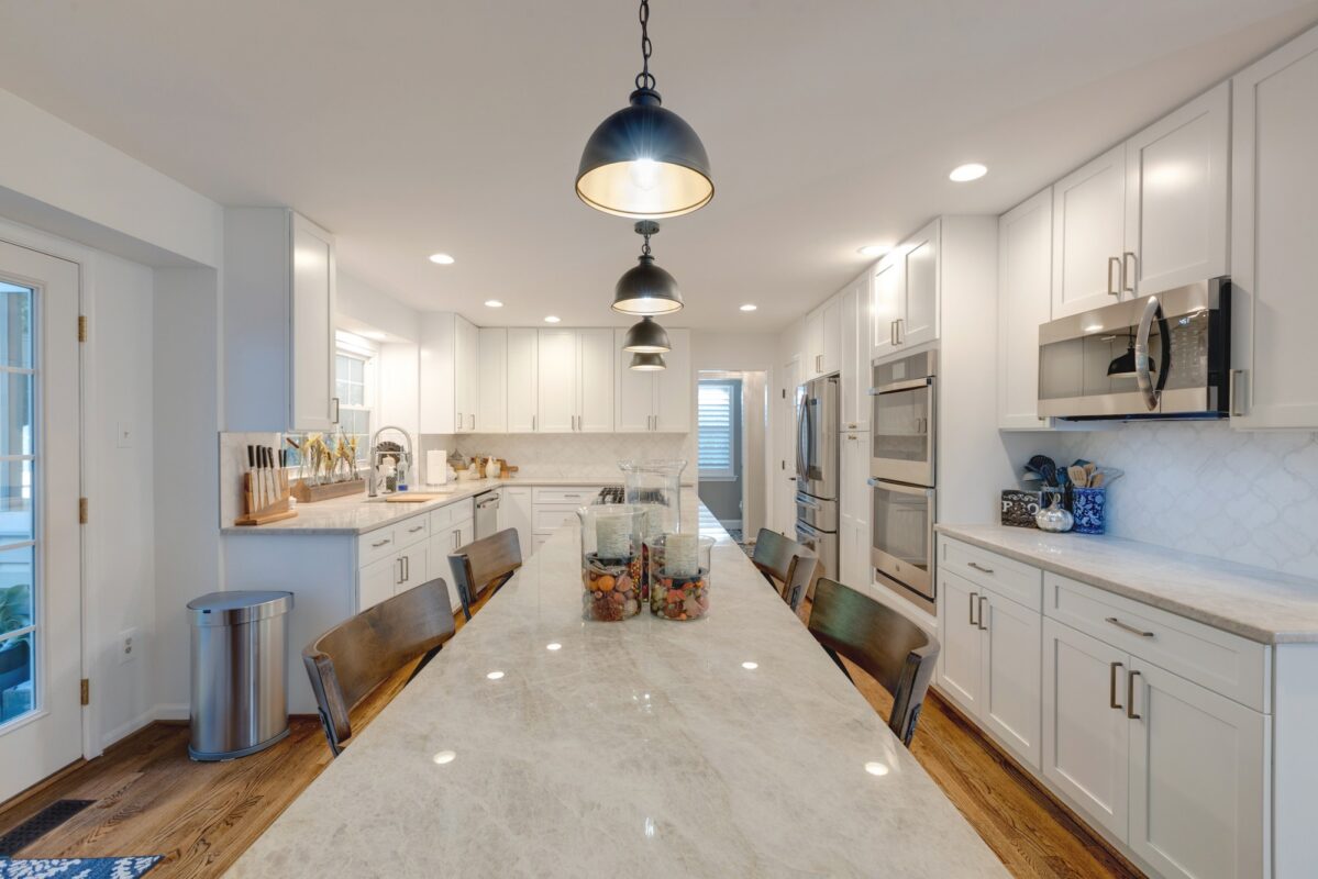 White kitchen with long quartzite island and black dome pendant lights