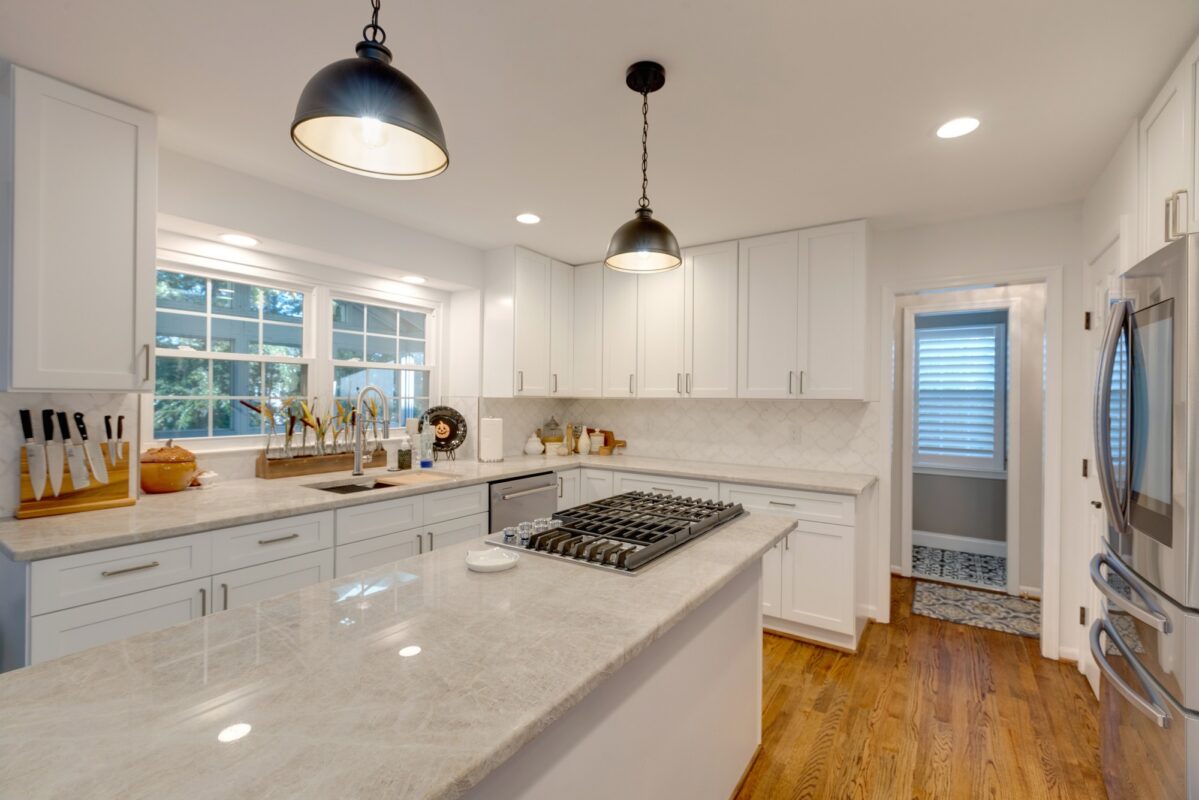 White kitchen with gas cooktop island, quartzite counters and dome pendants