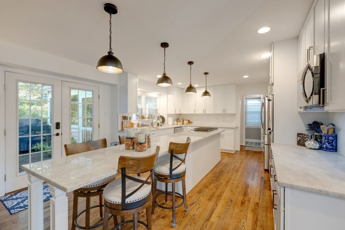 White kitchen with seating island, pendant lights and French doors