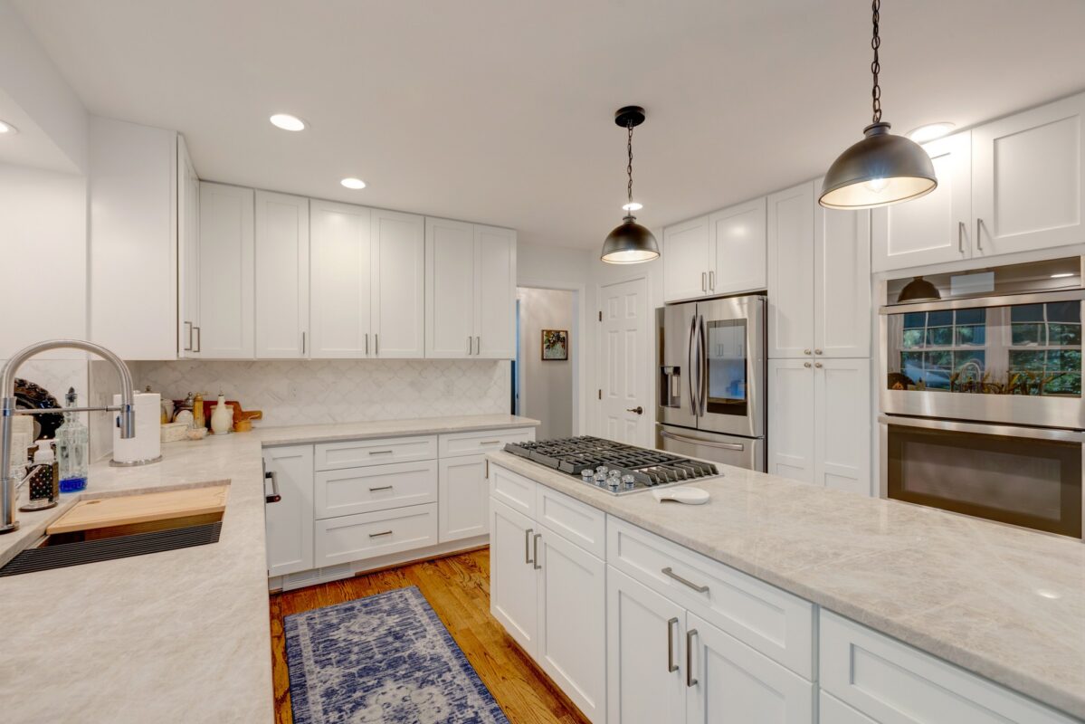 White kitchen with island cooktop and black pendant lights